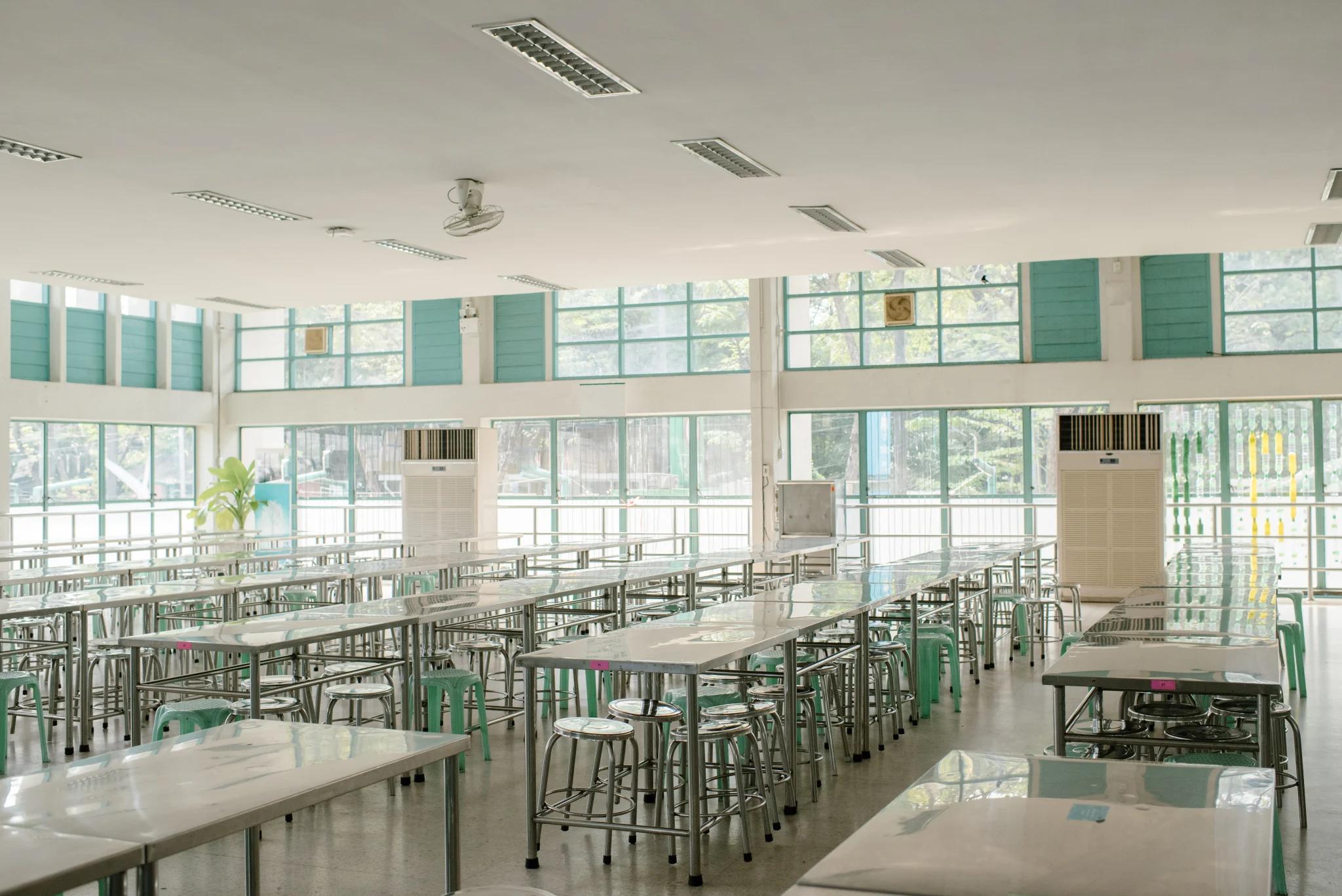 large classroom with tables and chairs facing front of room surroundd by glass window walls at higher education facility