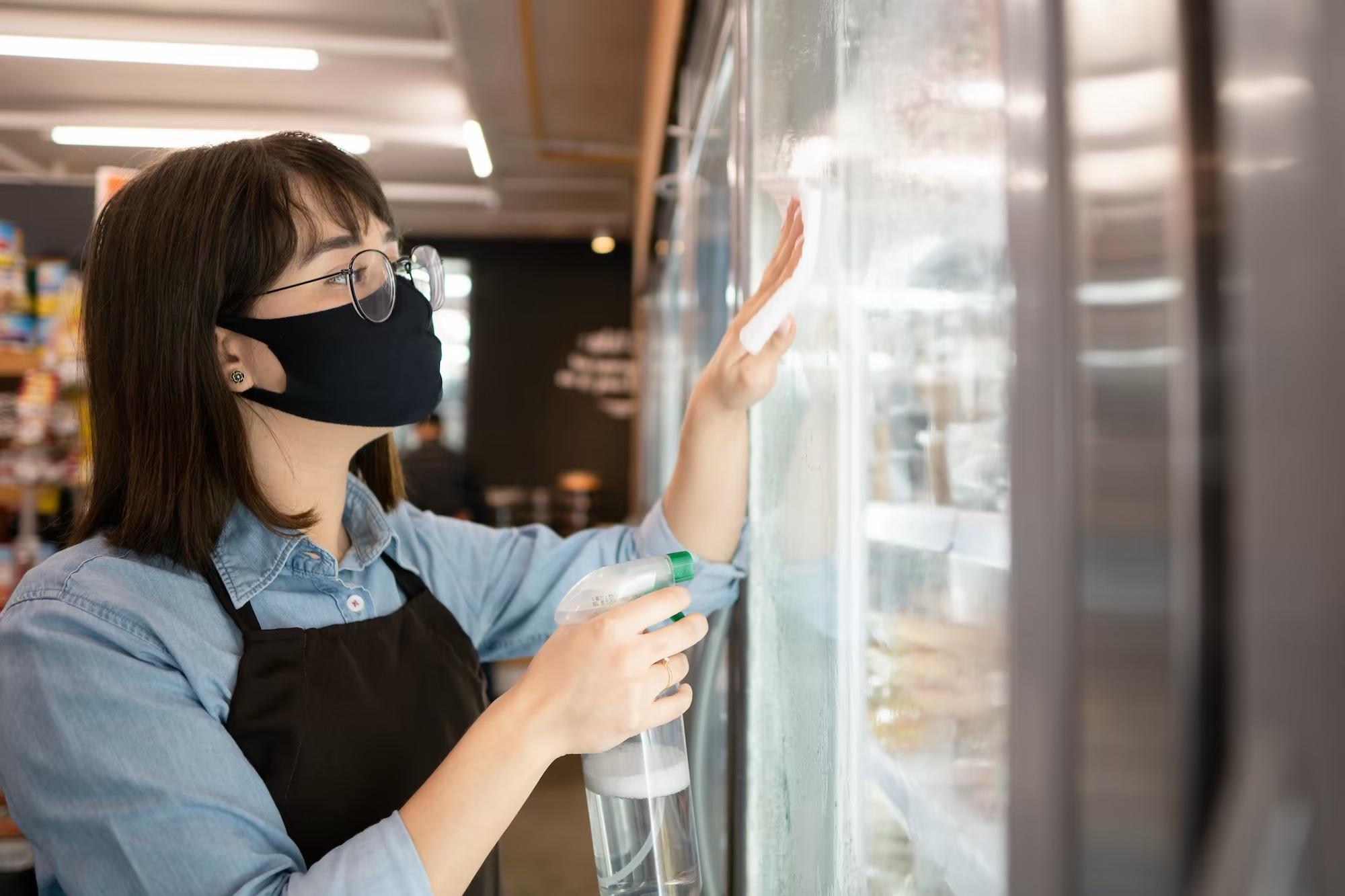 grocery store retail employee cleaning cooler doors